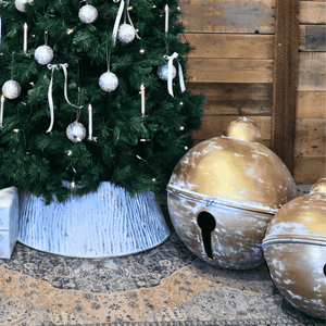 Decorative Christmas tree with ornaments and large christmas bells on a the floor.