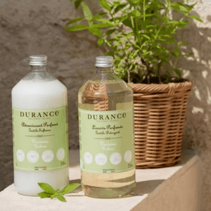 Durance Verbena Laundry Detergent and Fabric Softener bottles in sunlit Provençal setting with fresh greenery – natural French laundry care