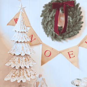 Close-up of embossed gold detailing on tiered metal Christmas tree with Noel Bunting