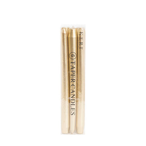 Box of gold taper candles on neutral background
