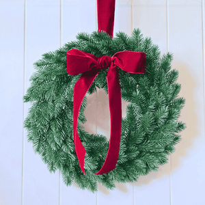 Wreath with velvet bow hung on white panel door – elegant holiday decor
