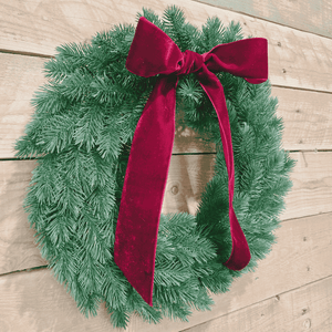 Green Christmas wreath with a red velvet bow on a wooden background