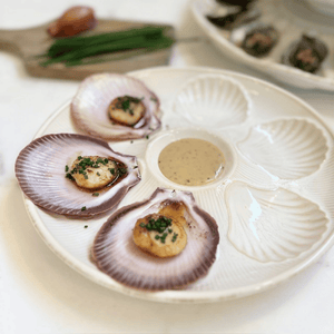 Scallops on a decorative Bessin Scallop Plate dish with a sauce in the center.