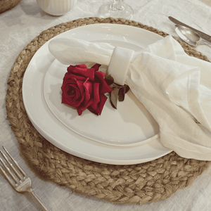French Flax Napkin White - Place setting with a red rose on a white plate, surrounded by cutlery and a woven placemat.