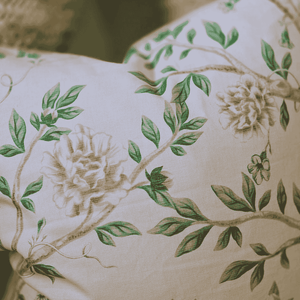 Close-up of a decorative pillow with floral and leaf patterns on a beige background