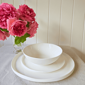 Amitié 12 piece white ceramic dinner set on table with roses in a glass