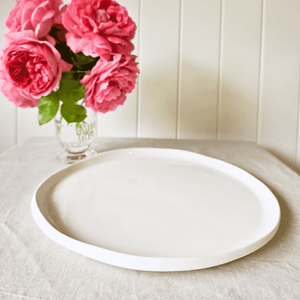 Amitié white ceramic dinner plate set on table with roses