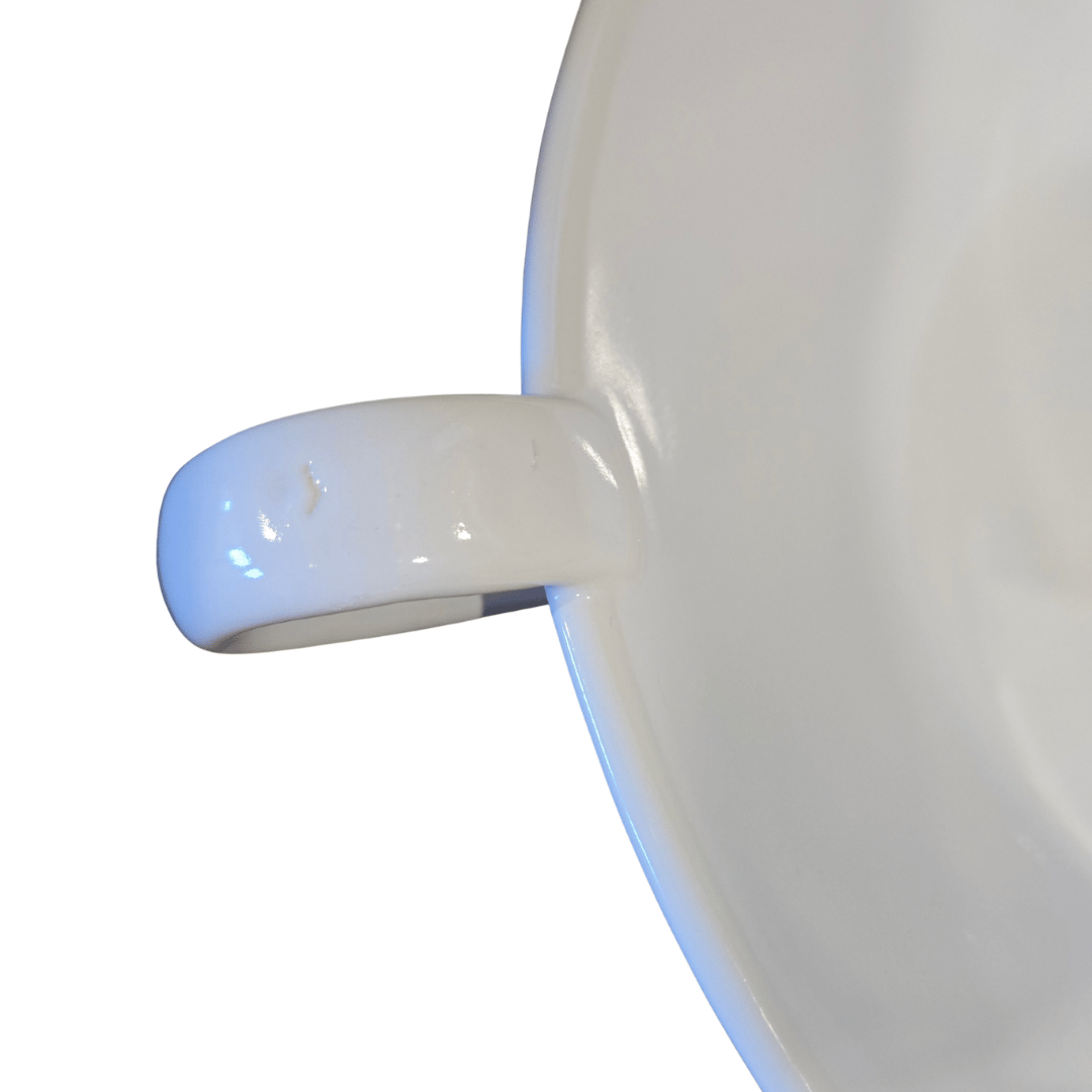 Close-up of a white ceramic bowl with a handle on a white background