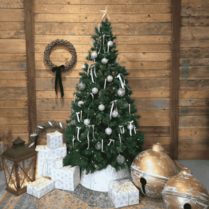Decorated Christmas tree with ornaments and presents against a wooden wall.  Oversized gold Christmas bells  – Malmaison Noël décor