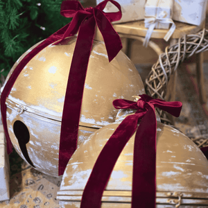 Decorative gold Christmas Bells with velvet red ribbons in a festive setting