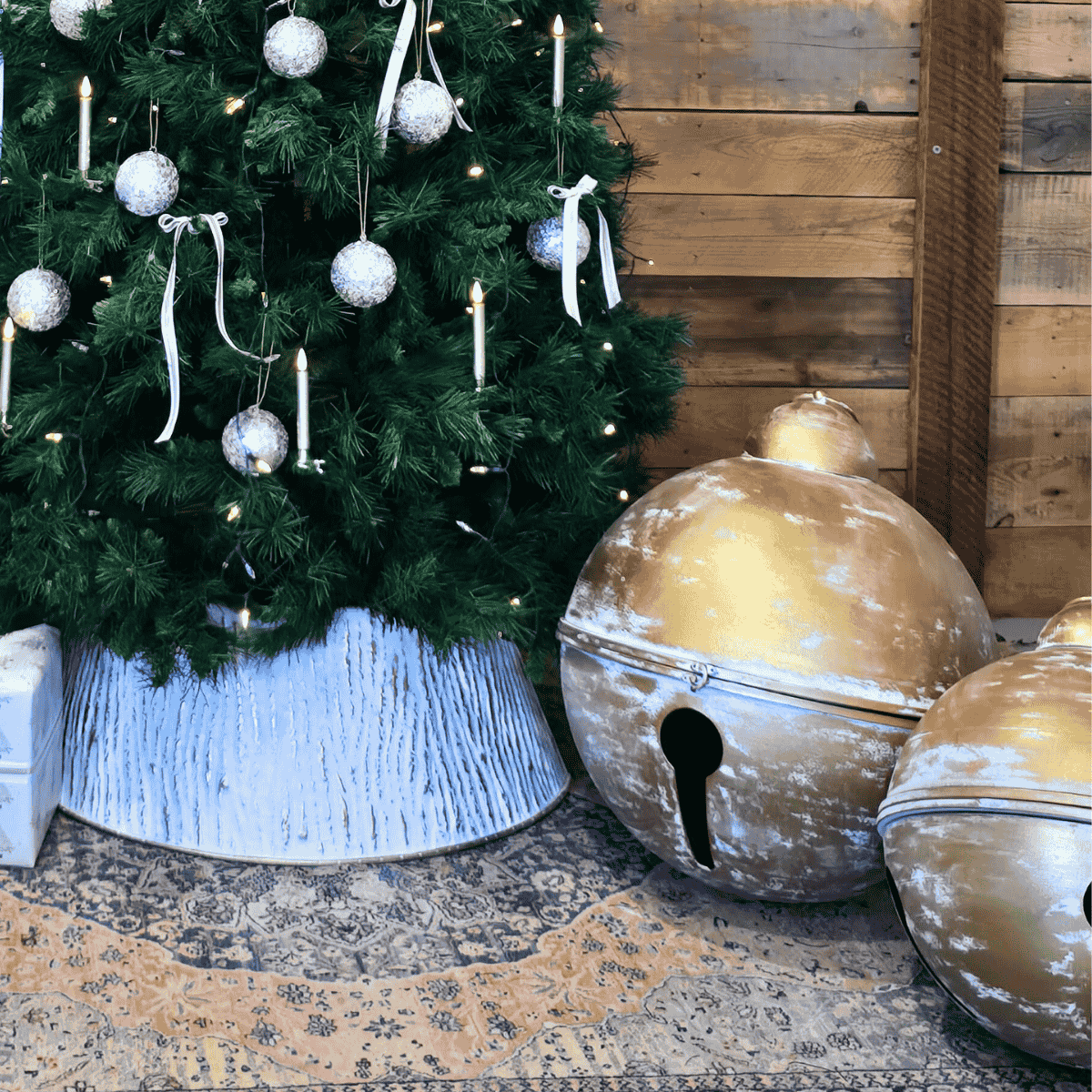 Decorative Christmas tree with ornaments and large christmas bells on a the floor.