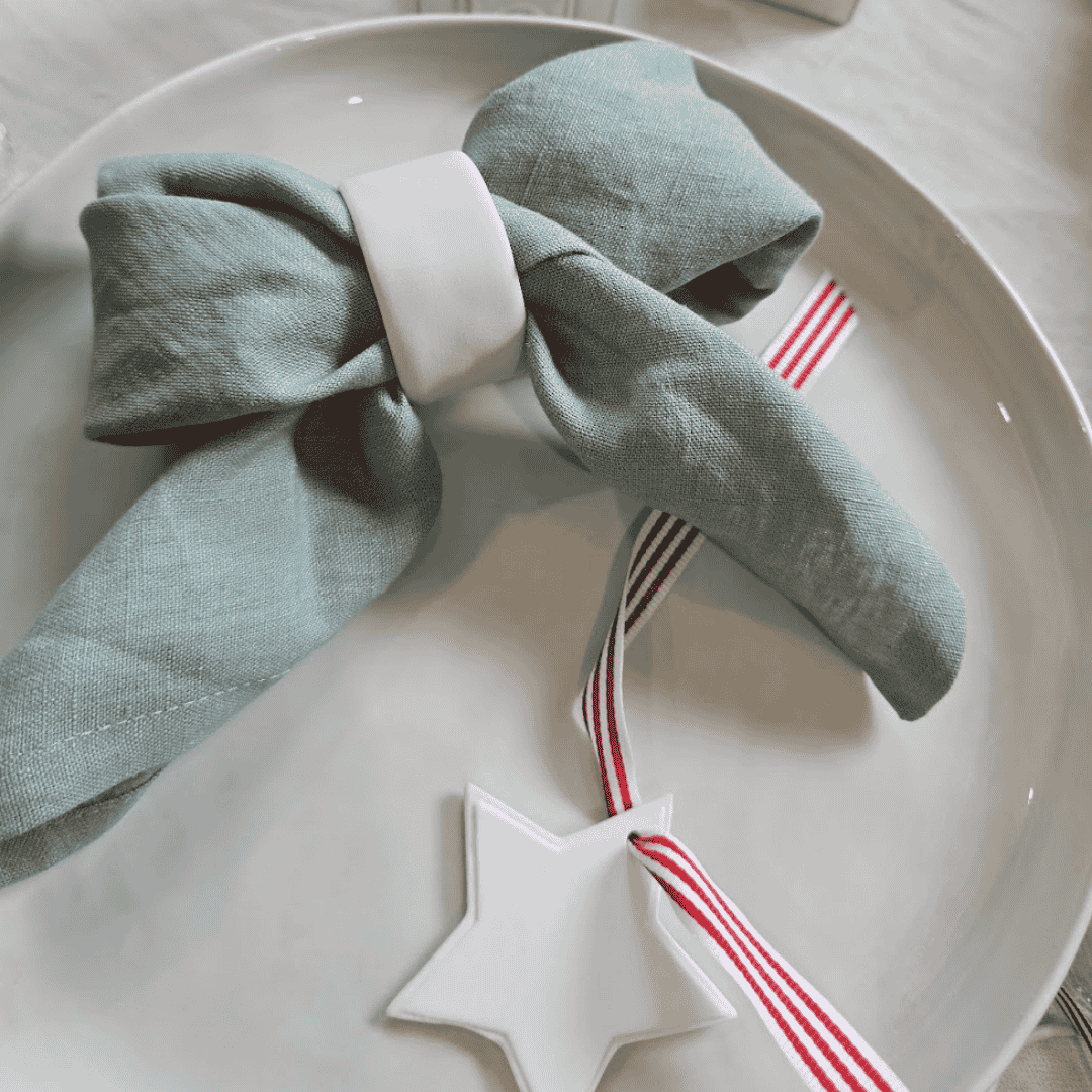 Mint linen napkin styled with white ceramic napkin ring and plate and christmas star