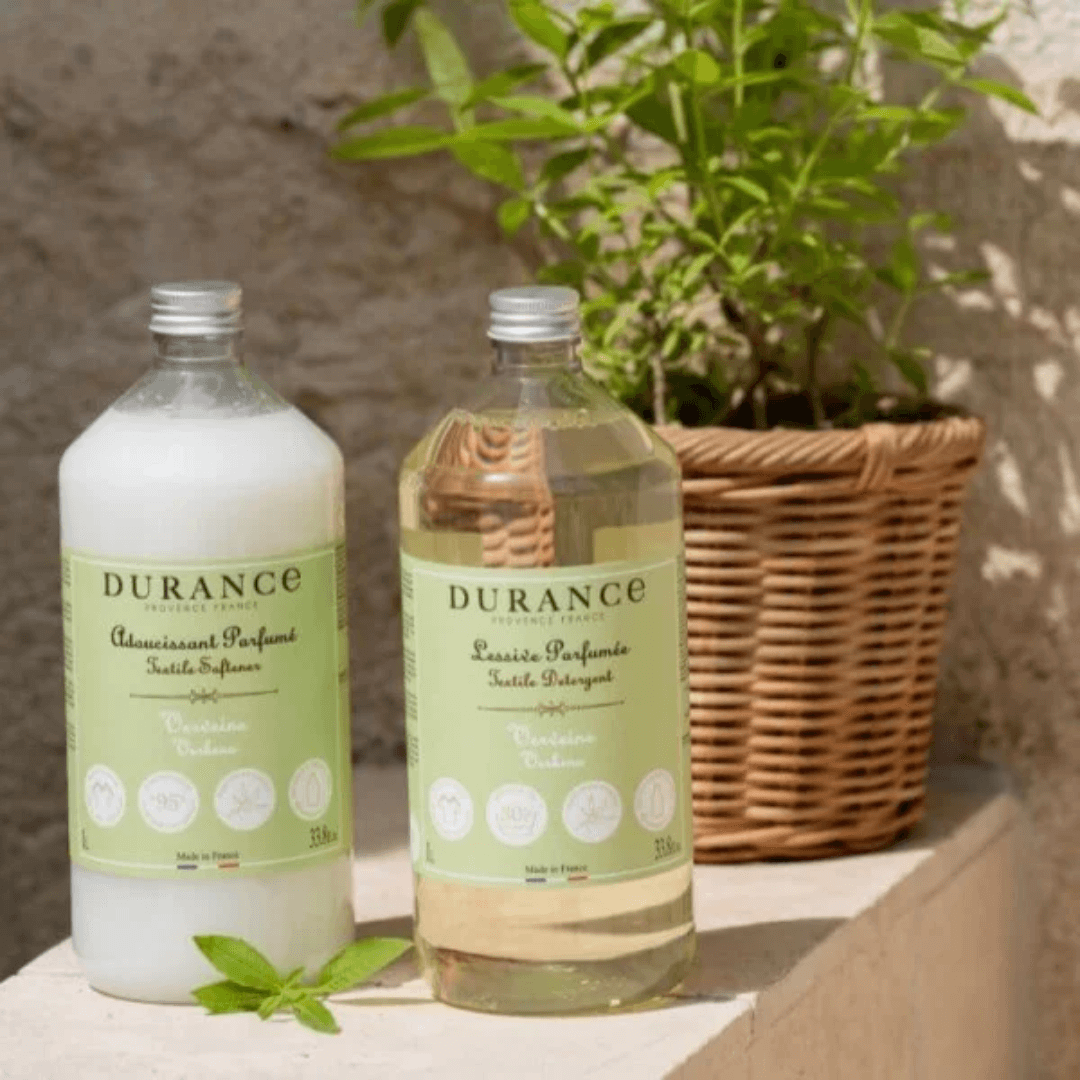 Durance Verbena Laundry Detergent and Fabric Softener bottles in sunlit Provençal setting with fresh greenery – natural French laundry care