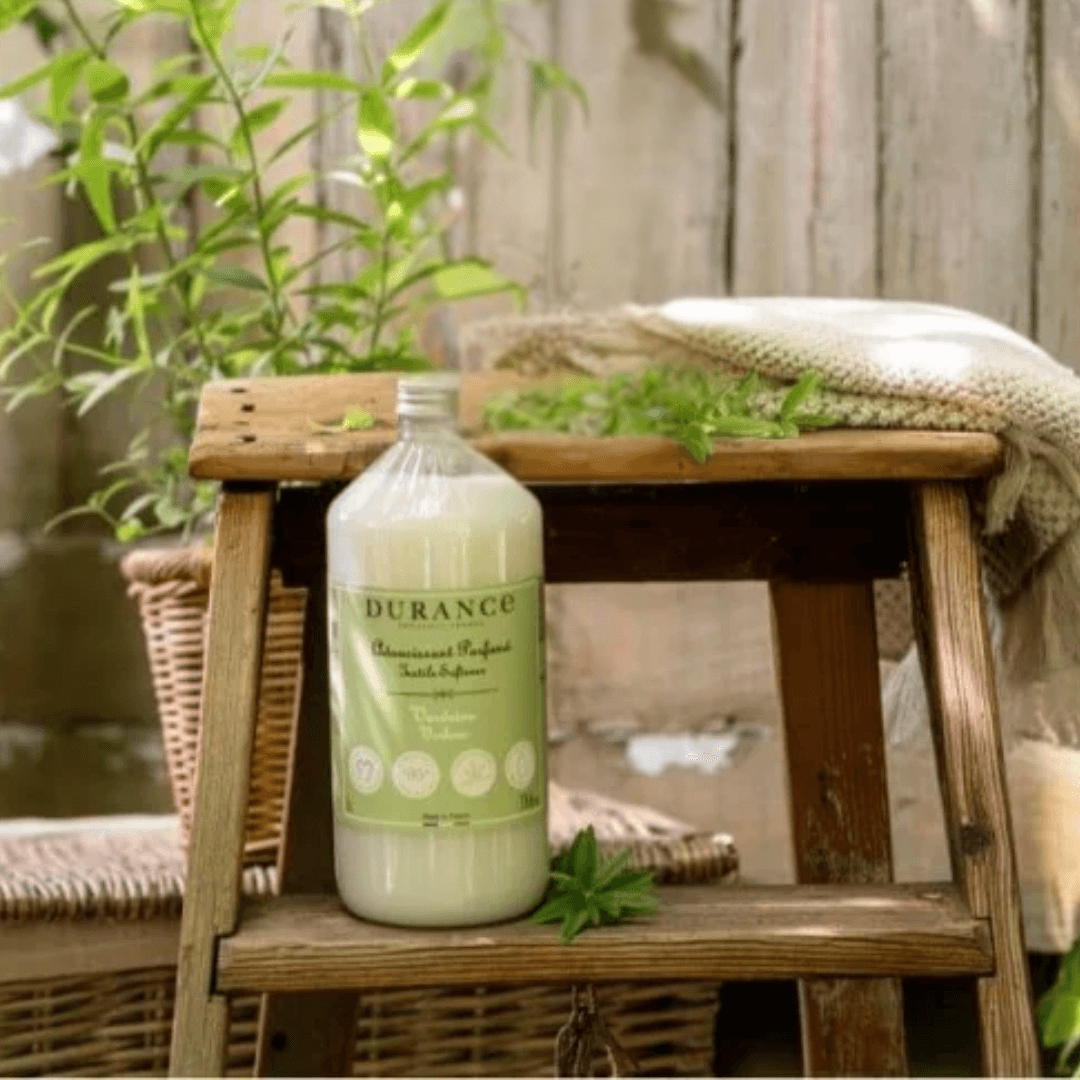 Durance Verbena Fabric Softener bottle in sunlight beside a potted herb – clean, green French laundry care infused with natural vitality.