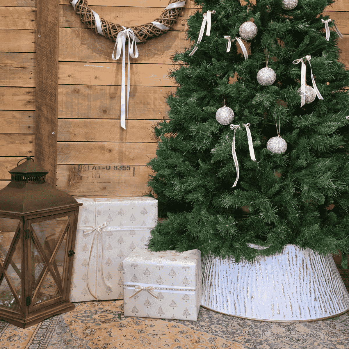 White and gold metal Christmas tree skirt with wrapped gifts beside tree