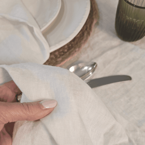Close-up of a French Flaxa white tablecloth with a plate, spoon, and knife in the background.