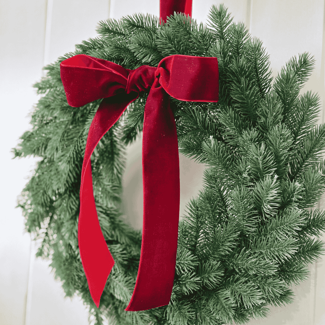 Green Christmas wreath with a red bow on a white background