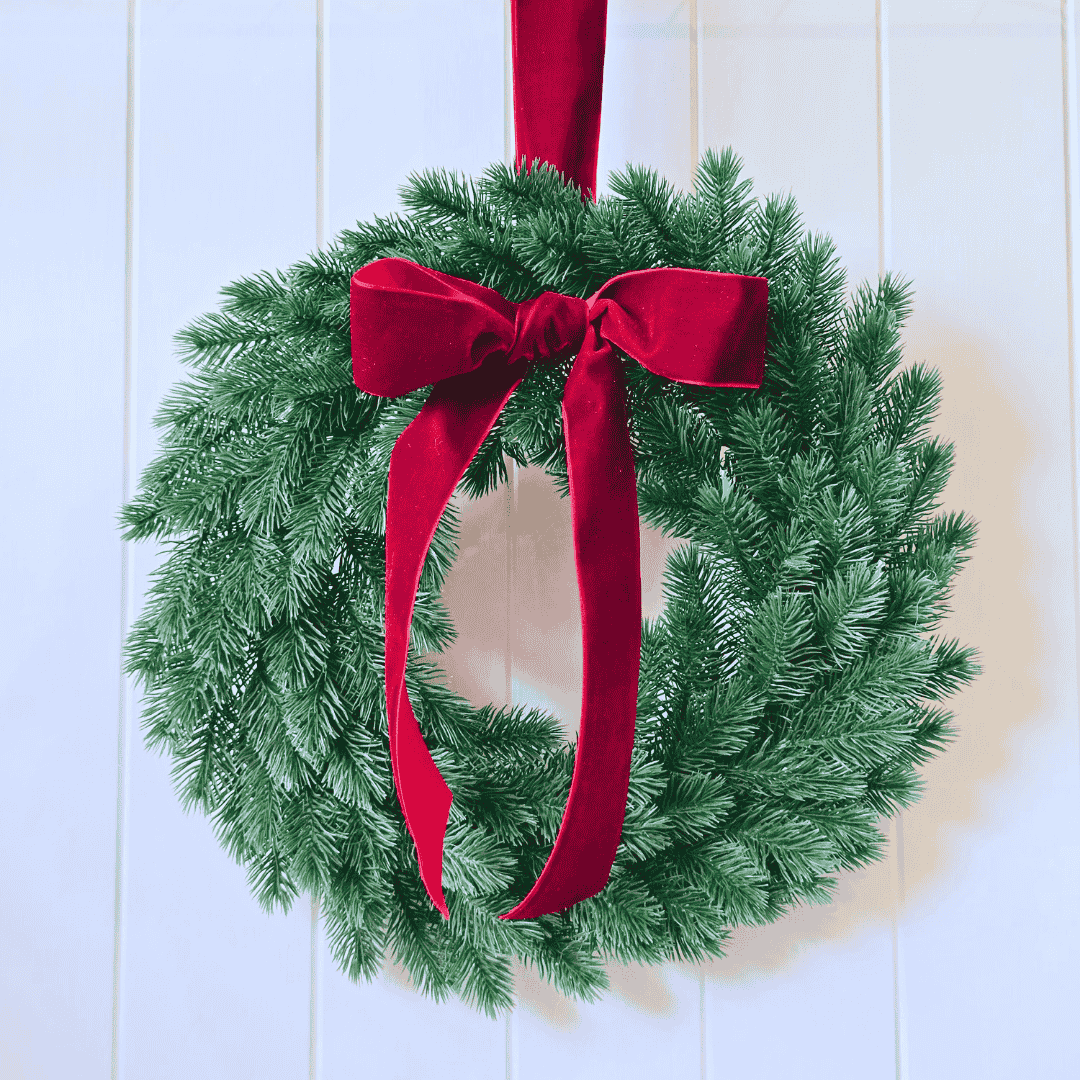 Wreath with velvet bow hung on white panel door – elegant holiday decor