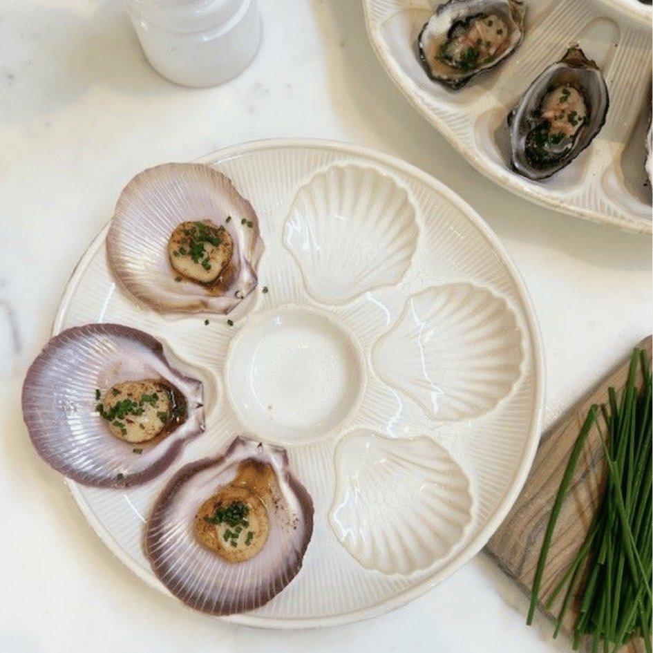 Scallops on a decorative Bessin Scallop Plate dish with a sauce in the center.