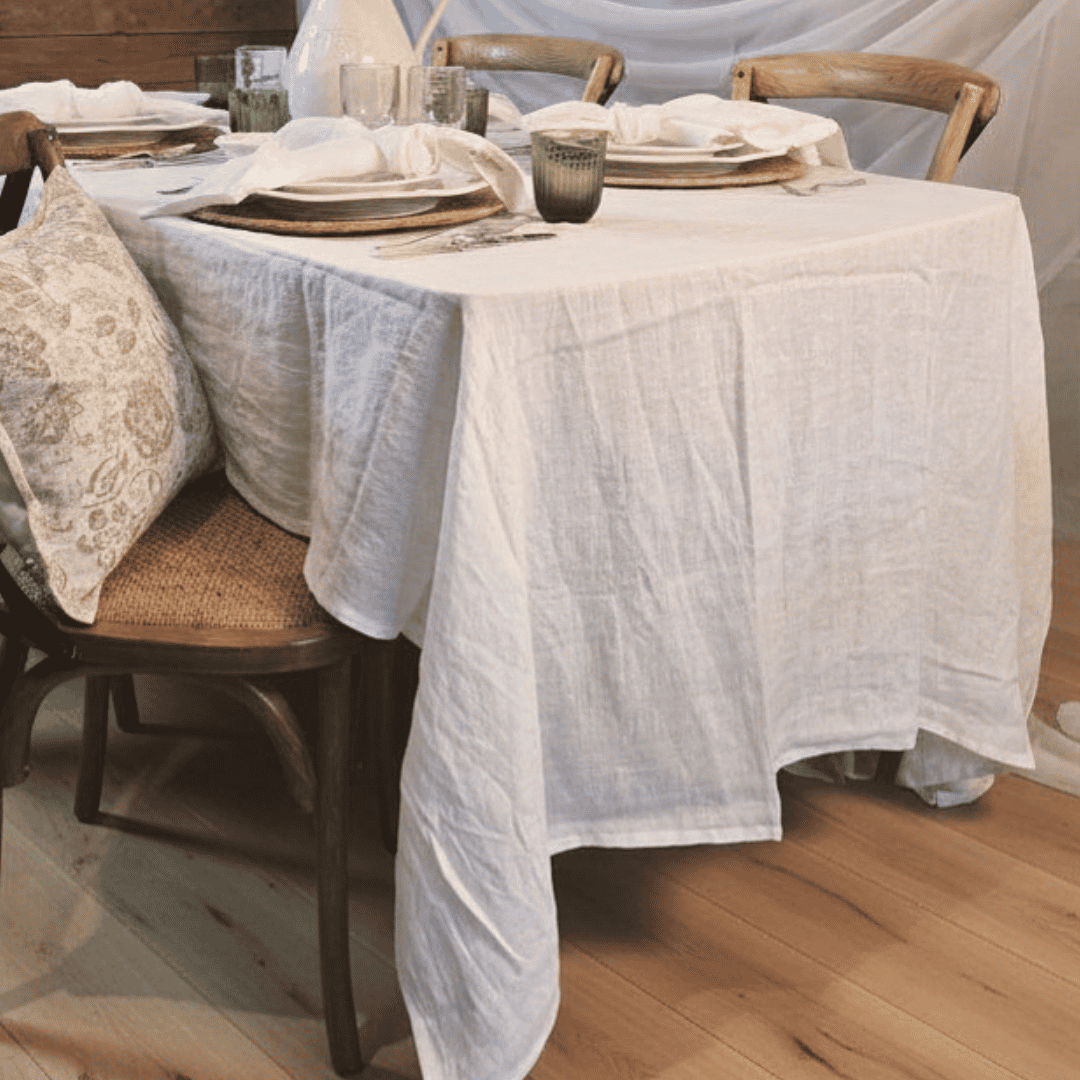 Dining table set with a white French Flax Linen tablecloth, plates, and glasses in a French Country setting.
