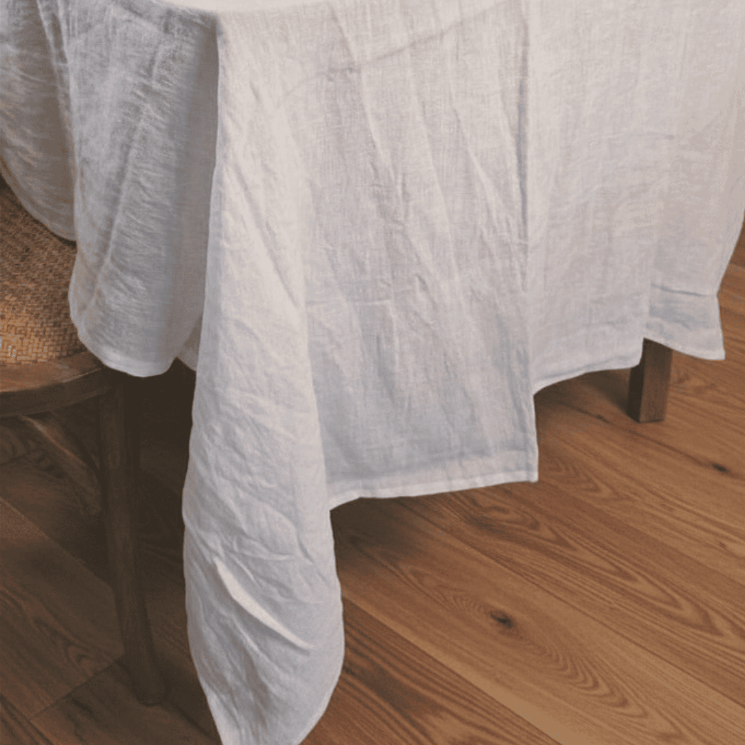Dining table set with a white French Flax Linen tablecloth, plates, and glasses in a French Country setting.