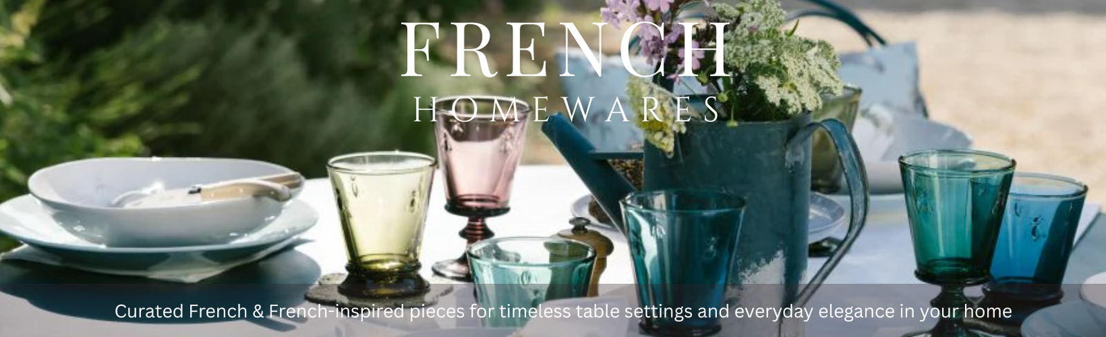 Table setting with colorful glassware and a vase of flowers, featuring 'French Home Wares' branding.