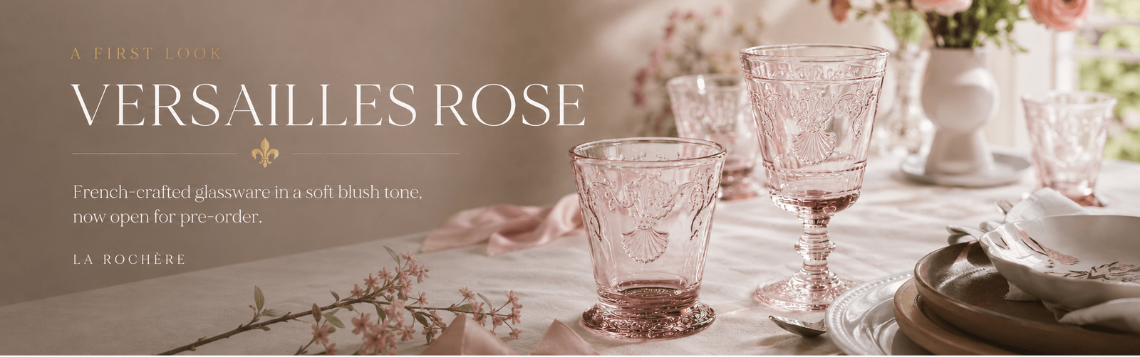 La Rochere 'Versailles Rose' French crafted glassware in a blush pink tone, shown in a beautifully styled dining table setting with floral accents and elegant tableware.