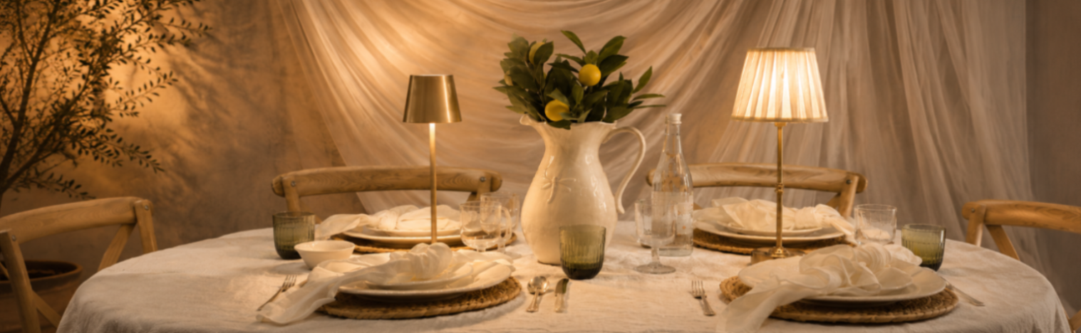 Dining table set with plates, cutlery, and a vase of flowers under draped fabric.