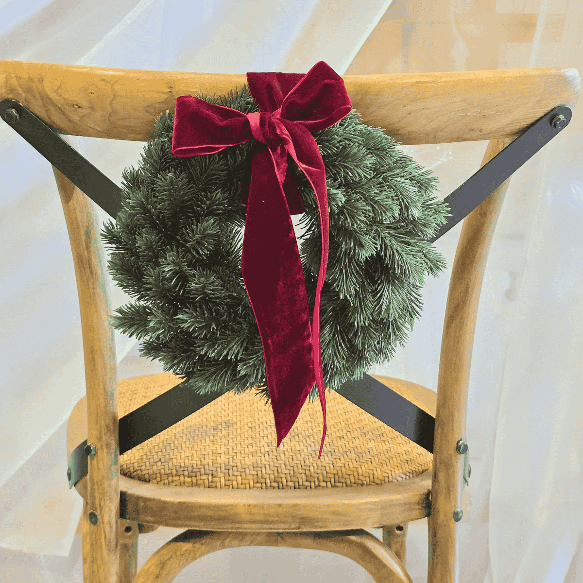Petite Traditional Christmas Wreath with red velvet bow tied to chair – Malmaison Noël décor