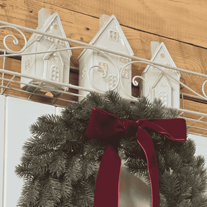 Glowing ceramic house display styled with wreath