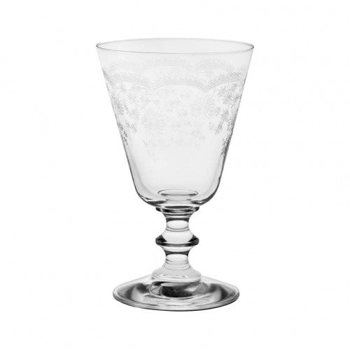 A clear crystal wine glass with etched floral patterns, displayed alongside a white cloth with an etched design.