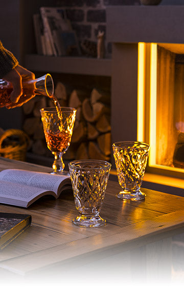 A clear glass Lyonnais tumbler with a teardrop shape and intricate floral pattern.