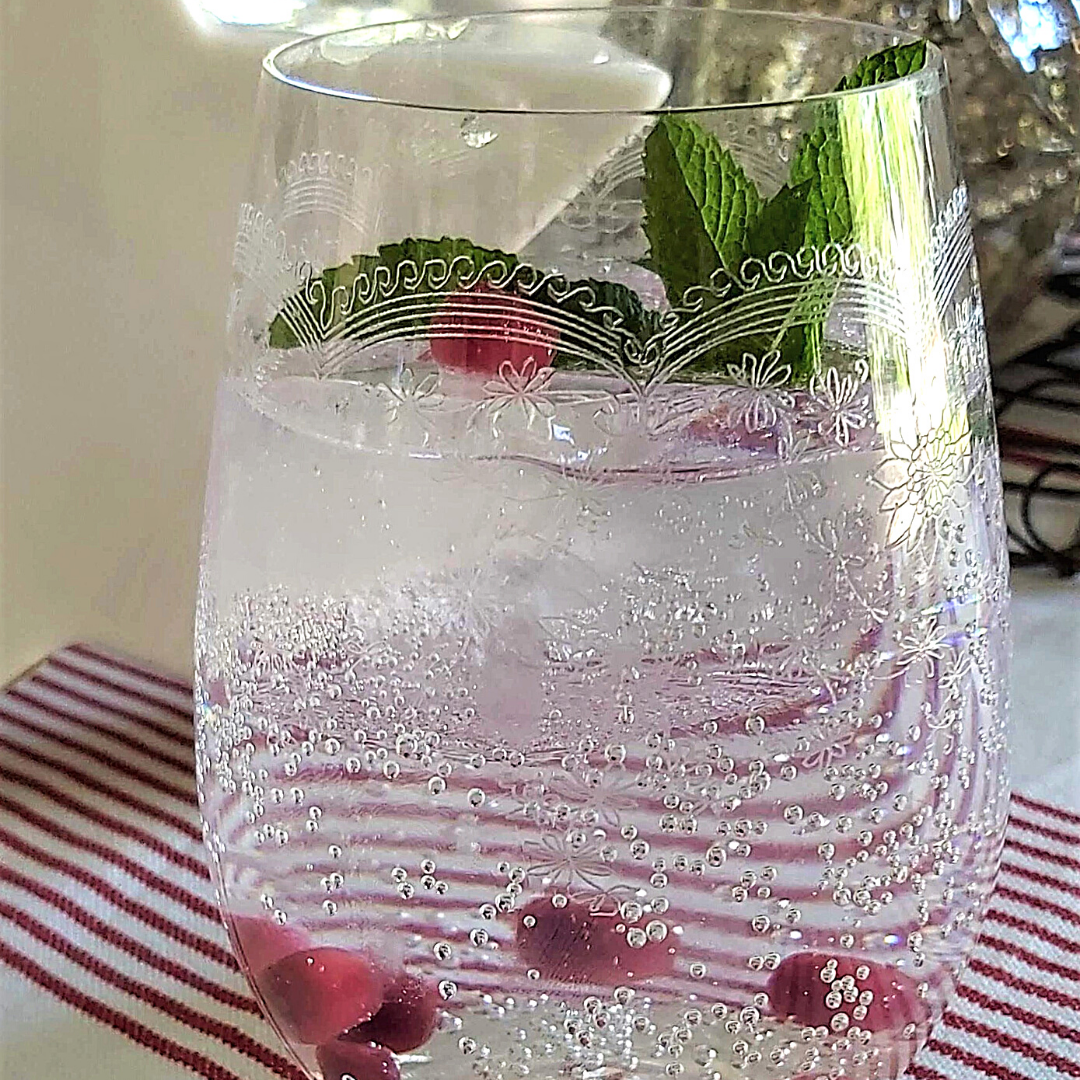Close up Stemless France Crystal Glass with sparkling water, raspberries and mint. French striped tablecloth